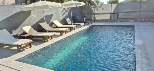 Villa Twins 23’ün özel yüzme havuzu, havuz başı şezlongları ve güneşlenme alanıyla keyifli bir tatil ortamı sunuyor.