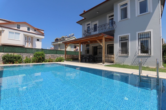 Özel yüzme havuzunun farklı açıdan görünümü ve villa dış cephesi. Fethiye'de havuzlu villa arayan misafirler için konforlu bir konaklama seçeneğidir.