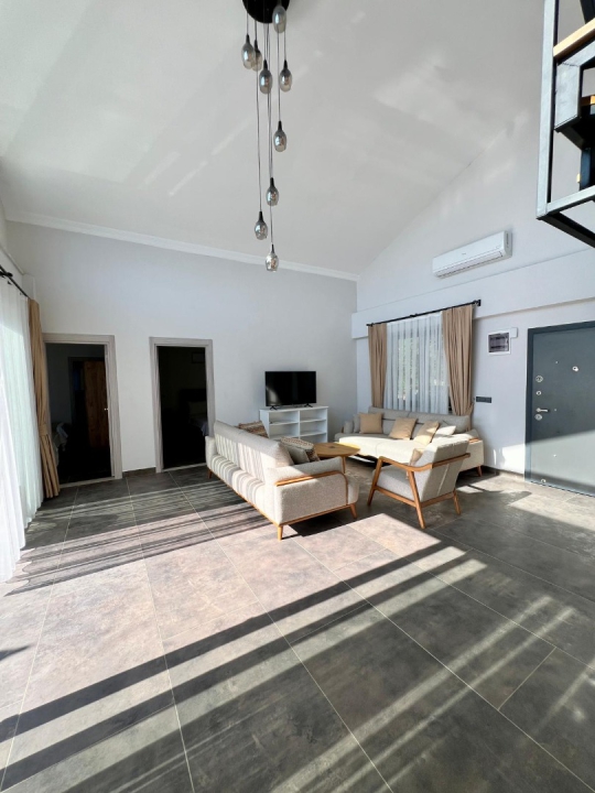 Villa Kresivaya Duo 1'in Fethiye Faralya'daki şık salonu, konforlu oturma grubu ve havuz manzaralı yaşam alanı.