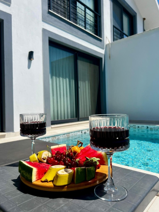 Fethiye Faralya'daki Villa Kresivaya Duo 1'in özel havuz kenarında keyifli sunum alanı ve konforlu tatil atmosferi.