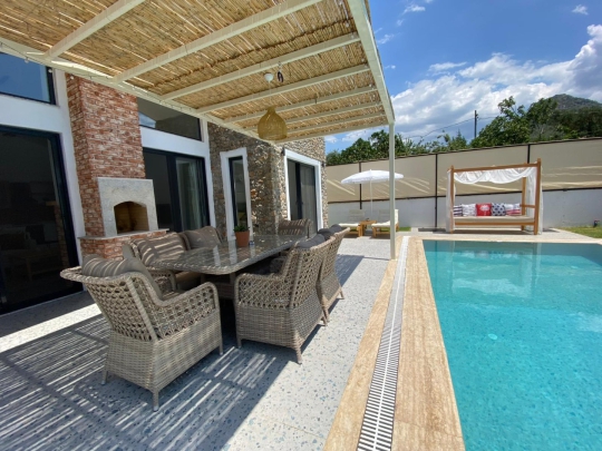 Fethiye Kayaköy'deki Villa Olipos'un havuz başı oturma alanı, barbekü köşesi ve keyifli açık yaşam alanı.