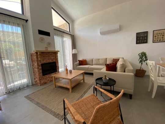 Villa Olipos Duo'nun şömineli, ferah ve konforlu oturma alanını gösteren modern salon tasarımı.