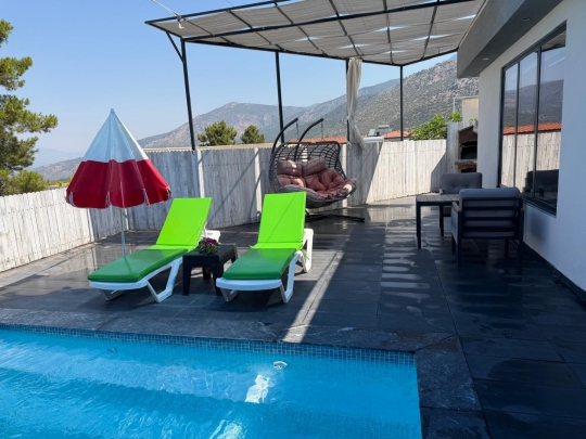 Villa Loli'nin özel yüzme havuzu, şezlong alanı ve doğa manzarasıyla romantik tatil atmosferi.