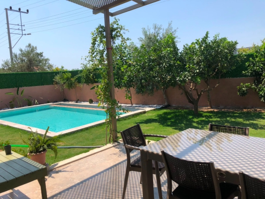 Villa La Luci'nin havuz manzaralı bahçe oturma alanı ve ailelere uygun ferah yaşam alanı.
