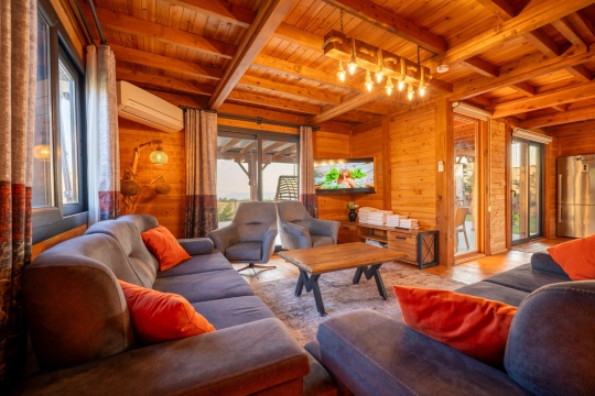 Villa Lamur'un geniş camları, ahşap dekorasyonu ve sıcak atmosfer sunan modern yaşam alanı.