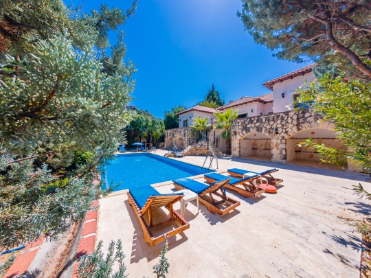 Villa Macha'nın geniş havuz terası ve şezlong alanıyla Kalkan'da aileler ve arkadaş grupları için konforlu villa.