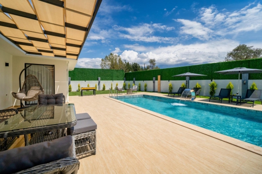 Villa West'in doğa manzarasına açılan geniş havuz terası ve korunaklı bahçe alanı.