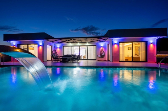 Villa West'in akşam aydınlatmalarıyla göz kamaştıran özel yüzme havuzu ve modern mimarisi.
