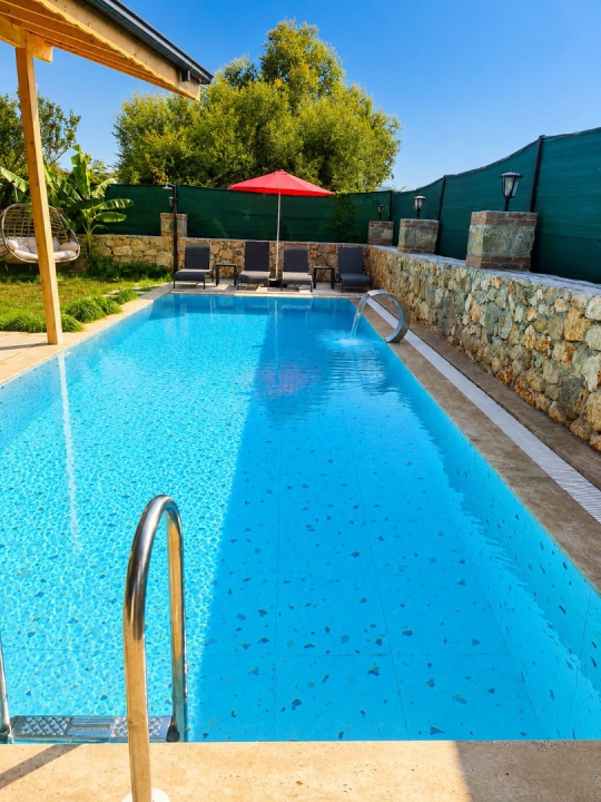 Villa Tint'in uzun özel yüzme havuzu, geniş güneşlenme alanı ve sakin doğa manzarası.