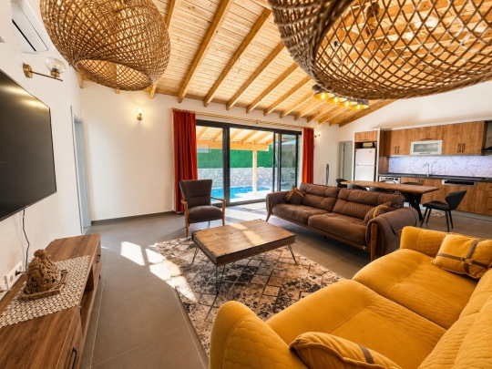 Villa Tint Duo'nun yüksek tavanlı ferah salonu ve havuz manzaralı modern yaşam alanı.