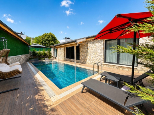 Kayaköy'deki Villa Tint Duo'nun modern taş mimarisi, özel havuzu ve geniş ahşap havuz terası.