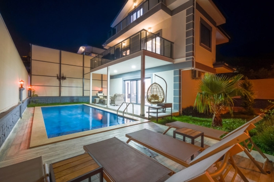 Villa Voi Duo'nun akşam ışıklandırmalı özel havuzu, modern terası ve jakuzili muhafazakar villa konseptiyle dikkat çeken bahçesi.