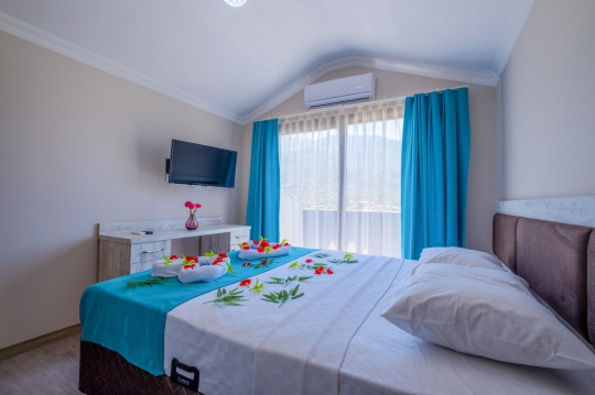 Vera Apart 2+1'in aydınlık yatak odası, konforlu yatağı ve ferah yaşam alanıyla Fethiye Esenköy'de dinlendirici bir tatil deneyimi sağlamaktadır.