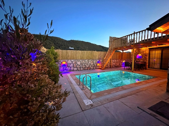 Fethiye Villa Soho’nun akşam saatlerinde aydınlatılan özel havuzu ve taş duvarlarla çevrili bahçesi romantik bir balayı atmosferi oluşturuyor.