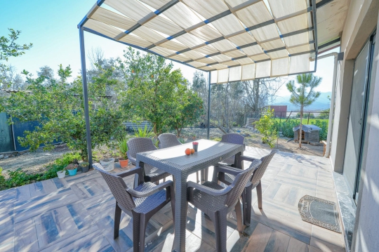 Saklıkent Tatil Evi 2 bahçesinde yer alan geniş veranda ve yemek masası. Aile tatilleri için ferah dış yaşam alanı.