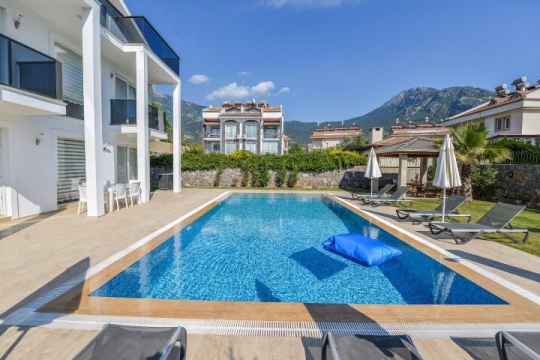 Fethiye Hisarönü Villa Şans’ın geniş özel yüzme havuzu, şezlongları ve güneşlenme alanıyla modern dış yaşam alanı.