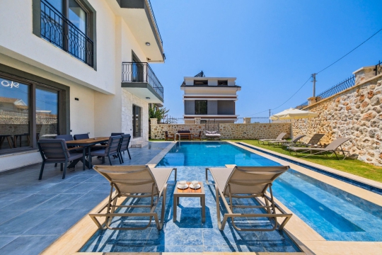 Fethiye Faralya Villa Rita 1’in özel yüzme havuzu, havuz başı yemek alanı ve modern villa dış cephe görünümü.