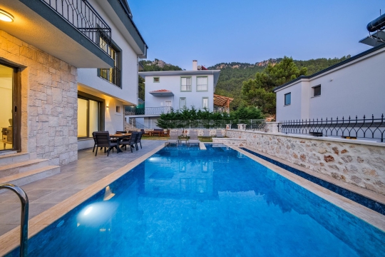 özel yüzme havuzu, havuz başı dinlenme alanı ve modern villa dış cephe görünümü.