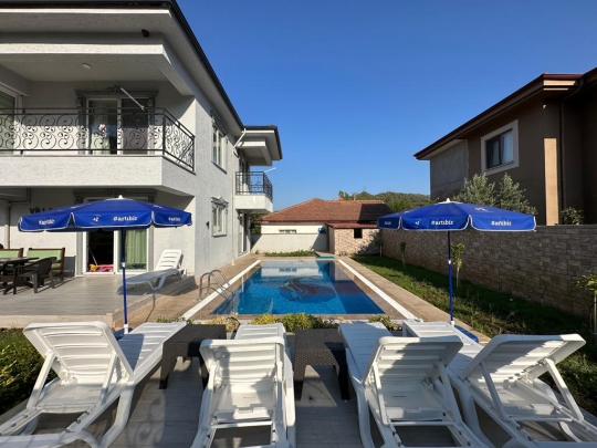 Villa Diamond 2’nin özel yüzme havuzu, şezlong ve şemsiyelerle düzenlenmiş geniş havuz başı dinlenme alanı.