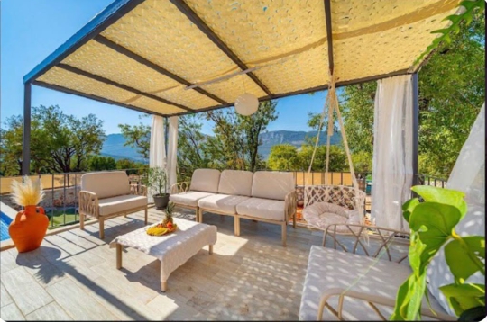 Villa Melodi’nin doğa manzarasına açılan gölgelikli bahçe oturma grubu ve konforlu açık hava dinlenme alanı.