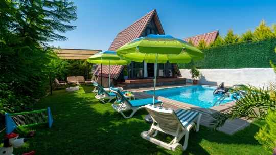 Villa Vega 1'in özel havuzu, güneşlenme alanı ve yemyeşil bahçesiyle huzurlu dış yaşam alanı.