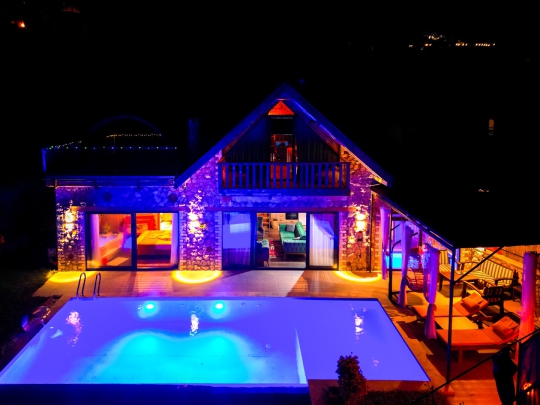 Villa Sunset Faralya’da gece aydınlatmalı havuz ve taş mimarili lüks villa görünümü