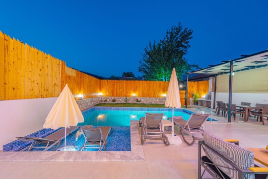 Villa Simos'un gece ışıklandırmalı özel havuzu ve şezlong alanıyla Kalkan Yeşilköy'de huzurlu villa tatili sizi bekliyor.