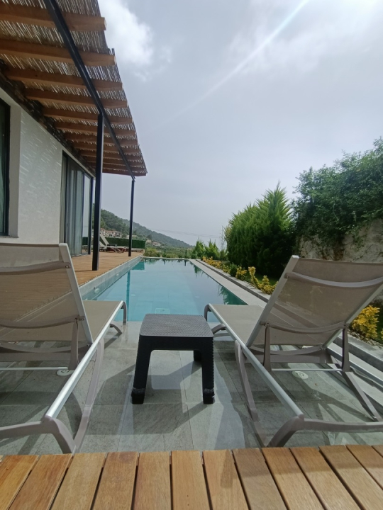 Villa Twins 20’nin özel yüzme havuzu, havuz başı şezlongları ve doğa manzarasına açılan ferah dinlenme alanı.
