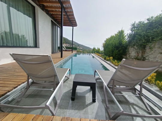 Faralya kiralık Villa Twins 20’de özel havuz başında şezlonglarla hazırlanmış dinlenme ve güneşlenme alanı.