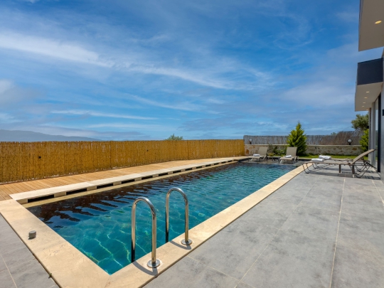 Villa Can Luxury'nin uzun özel yüzme havuzu ve geniş güneşlenme alanıyla Kalkan Çayköy'de huzurlu balayı ve aile tatili.