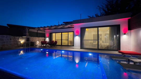 Villa Balies’in gece aydınlatmalarıyla öne çıkan özel havuzu ve modern dış cephesiyle romantik balayı villası görünümü.
