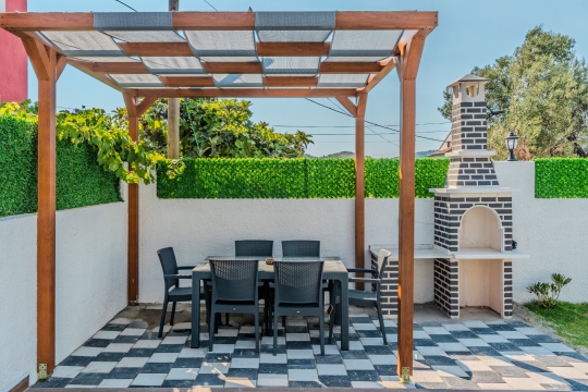 Fethiye Ölüdeniz'de bulunan Villa Nilda 2'nin pergolalı oturma alanı ve barbekü köşesiyle açık havada keyifli vakit geçirebileceğiniz bahçesi.