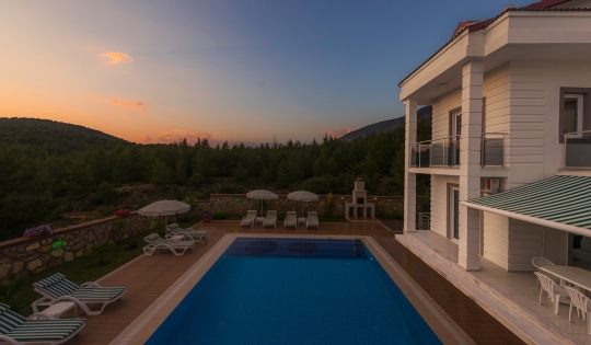 Ovacık’ın doğa ve dağ manzarasına açılan Villa Twins 11 özel havuzu ve gün batımında huzurlu dış yaşam alanı.