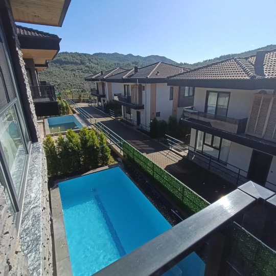 Yeşillikler içinde, şemsiye ve konforlu şezlonglarla donatılmış güneşlenme alanı.