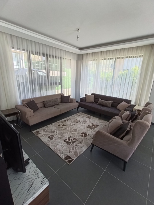 Geniş ve konforlu koltuk takımıyla, geniş pencerelerden havuz manzarasını izleyebileceğiniz ferah bir oturma odası.