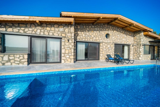 Villanın özel havuzu ve şezlong alanının modern mimariyle birleşimi.