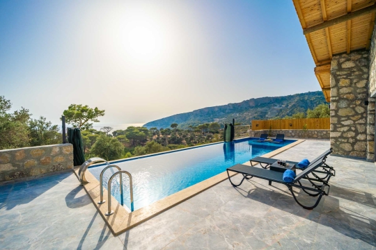 Villa terasında havuz başı keyfi için şezlonglar ve gün batımı manzarası.