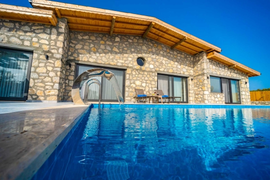 Villanın özel yüzme havuzu ve doğal taş duvarlı dış mimarisi.