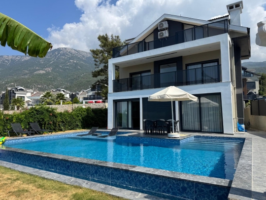 Villa Pan 1’in modern mimarisi, şezlong alanı ve Ölüdeniz’in doğasıyla bütünleşen özel havuz terası.