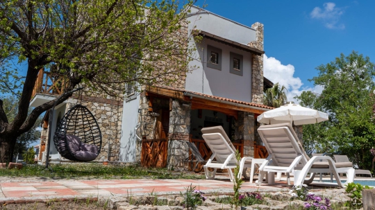 Bahçeden villaya bakış; begonviller ve taşın uyumu.