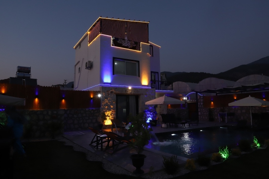 Mavi ve mor LED aydınlatmalar altında 3 katlı Villa Thor'un havuz başı gece atmosferi.