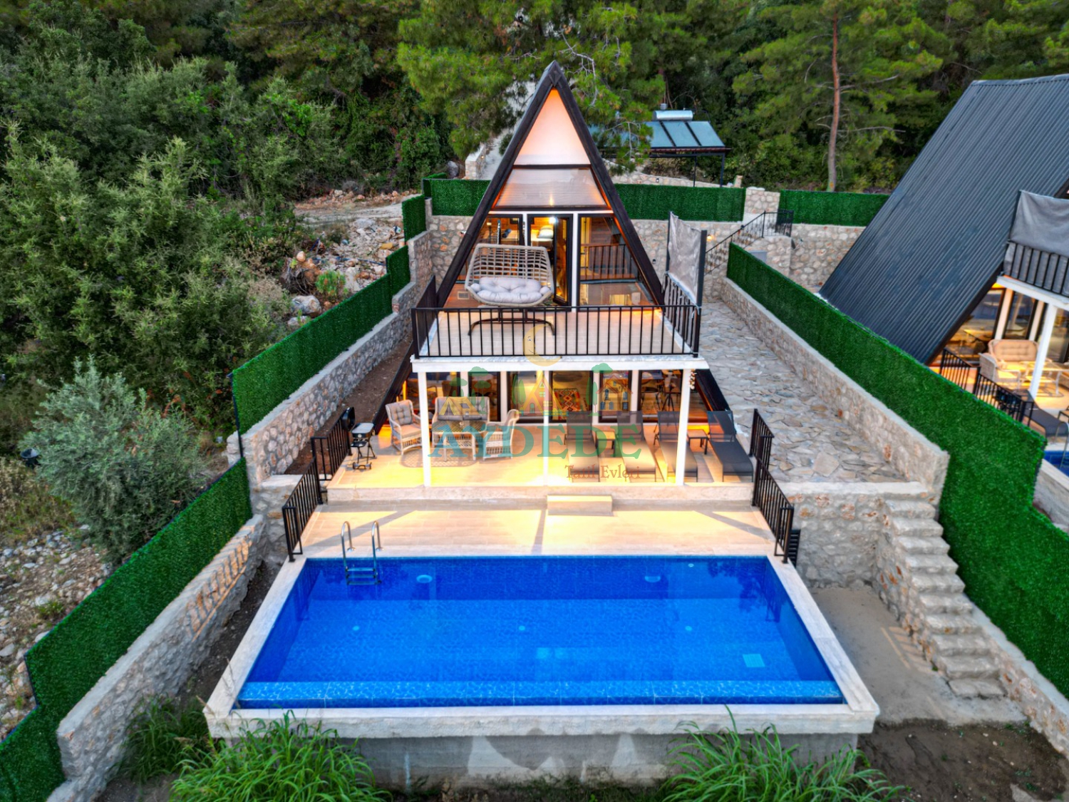 Kalkan Üzümlü'de yer alan Villa Mino'nun özel yüzme havuzu ve modern A tipi bungalov mimarisiyle dikkat çeken dış görünümü.