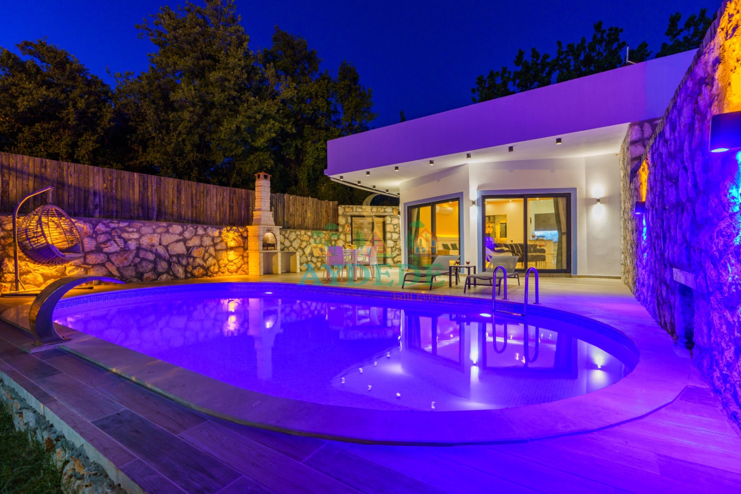 Villa Serter 1’in gece aydınlatmalı korunaklı özel havuzu ve modern mimarisiyle öne çıkan dış cephe görünümü. Kalkan Üzümlü’de balayı çiftleri için ideal muhafazakar villa seçeneği.
