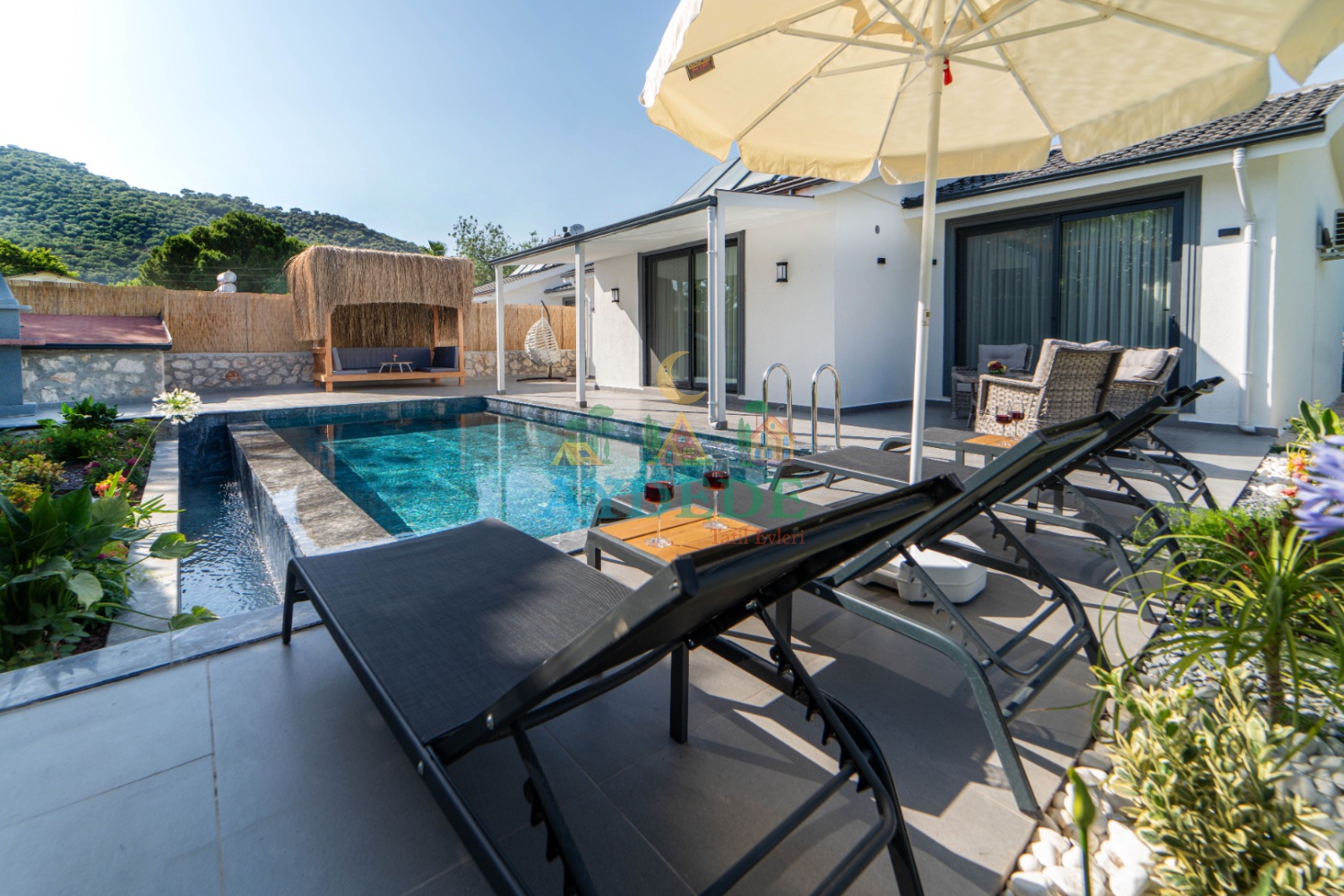 Villa Lita Duo'nun özel yüzme havuzu, geniş güneşlenme alanı ve modern bahçe mobilyalarıyla Fethiye Kayaköy'de konforlu villa tatili sunan dış alanı.