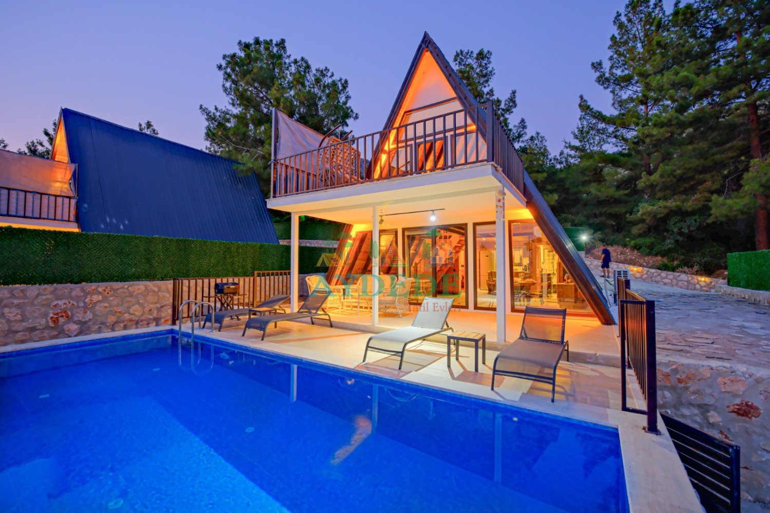 Kalkan Üzümlü'de bulunan Villa Mino Duo'nun özel yüzme havuzu ve modern A tipi bungalov mimarisiyle dikkat çeken akşam görünümü.