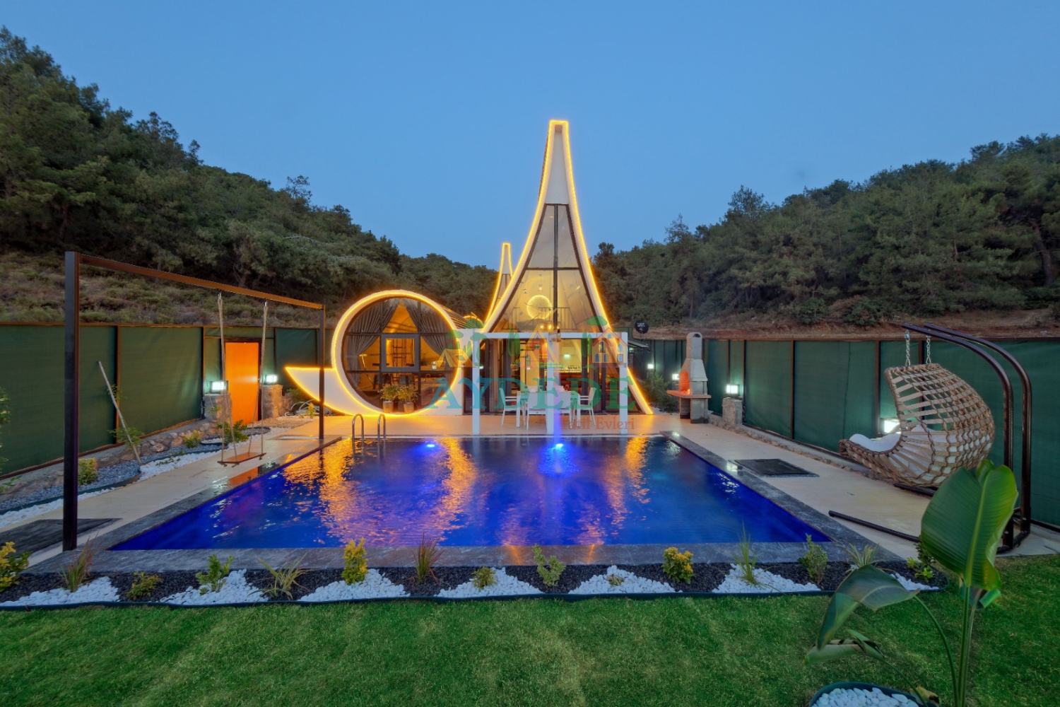 New Moon Bungalow'un akşam manzarasında ışıklandırılmış özel havuzu ve şık bungalov tasarımı.