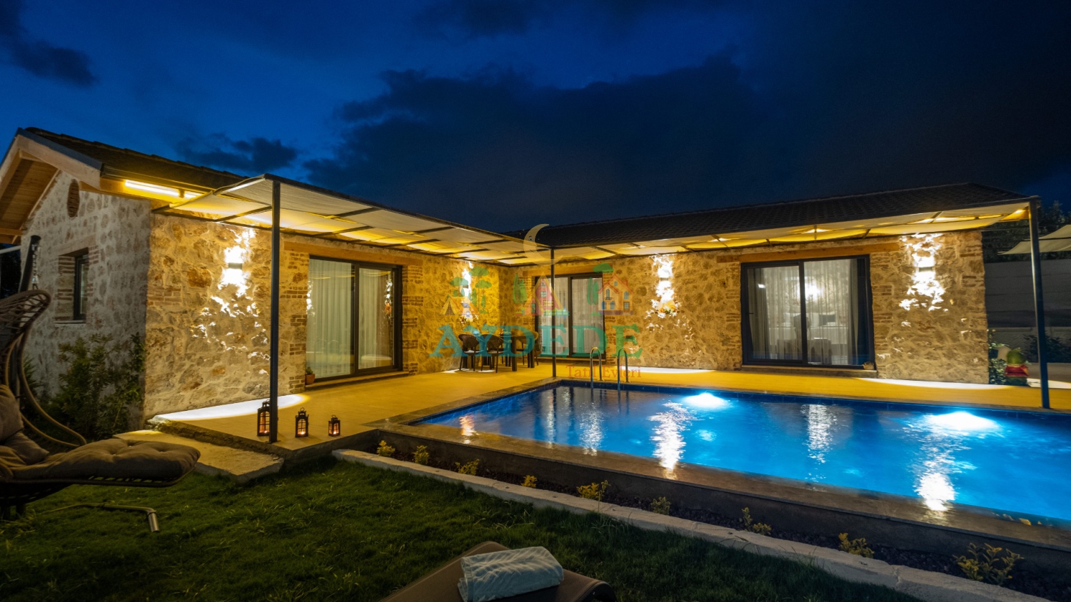 Villa Vira’da gece aydınlatmalı özel yüzme havuzu ve taş mimarili lüks villa görünümü