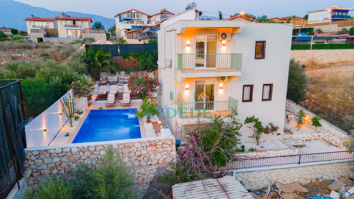 Kalkan Patara'da otantik taş mimariye sahip 2 katlı lüks Villa Romance'ın özel yüzme havuzu ve bahçe alanıyla gündüz görünümü.