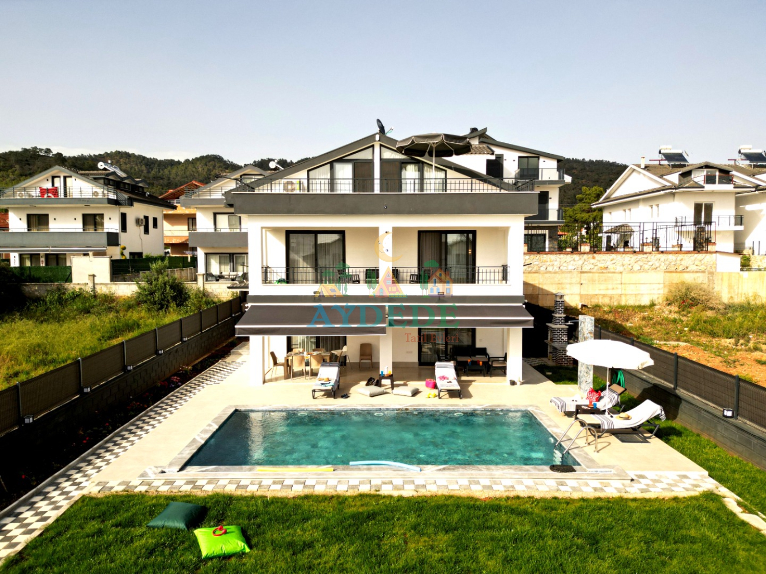 Villa Varoni Fethiye Çiftlik’te özel yüzme havuzu, geniş yeşil bahçesi ve modern dubleks mimarisiyle 12 kişilik tatil villası görünümü.