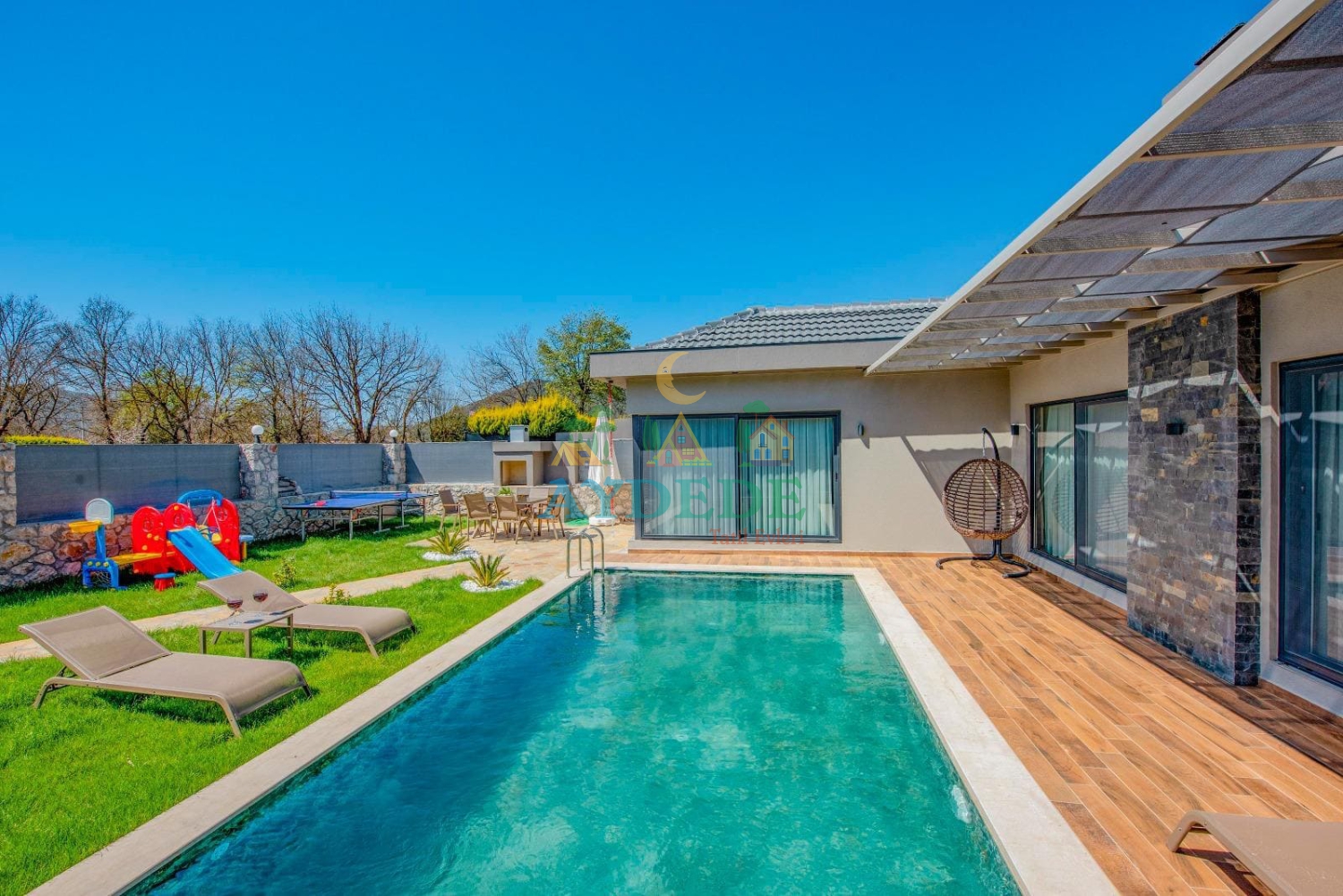 Fethiye Kayaköy’de konumlanan muhafazakar Villa Gardenella’nın korunaklı özel havuzu ve geniş bahçeli modern dış cephesi görünümü.